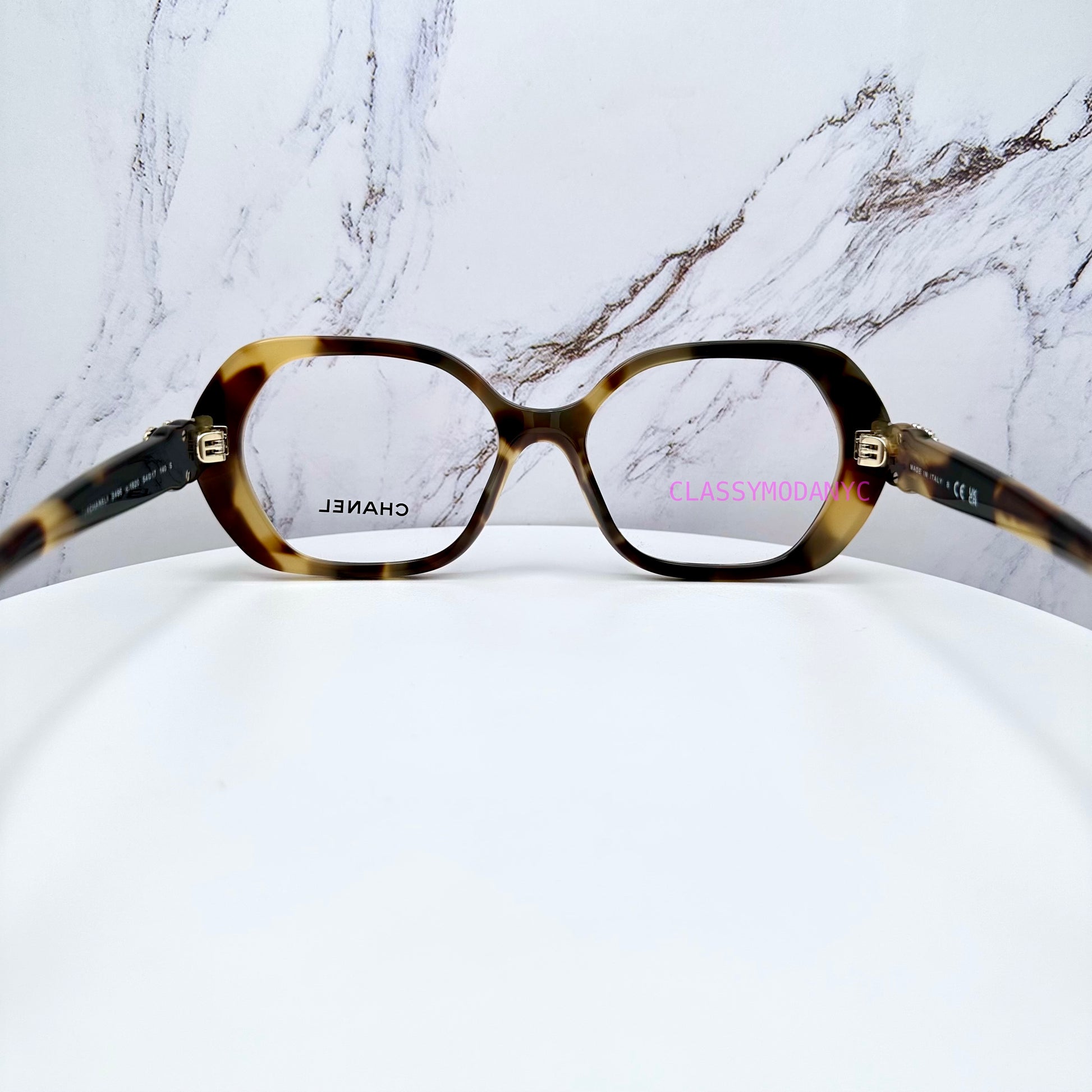 Chanel Tortoiseshell glasses on a white surface with a marble-patterned background