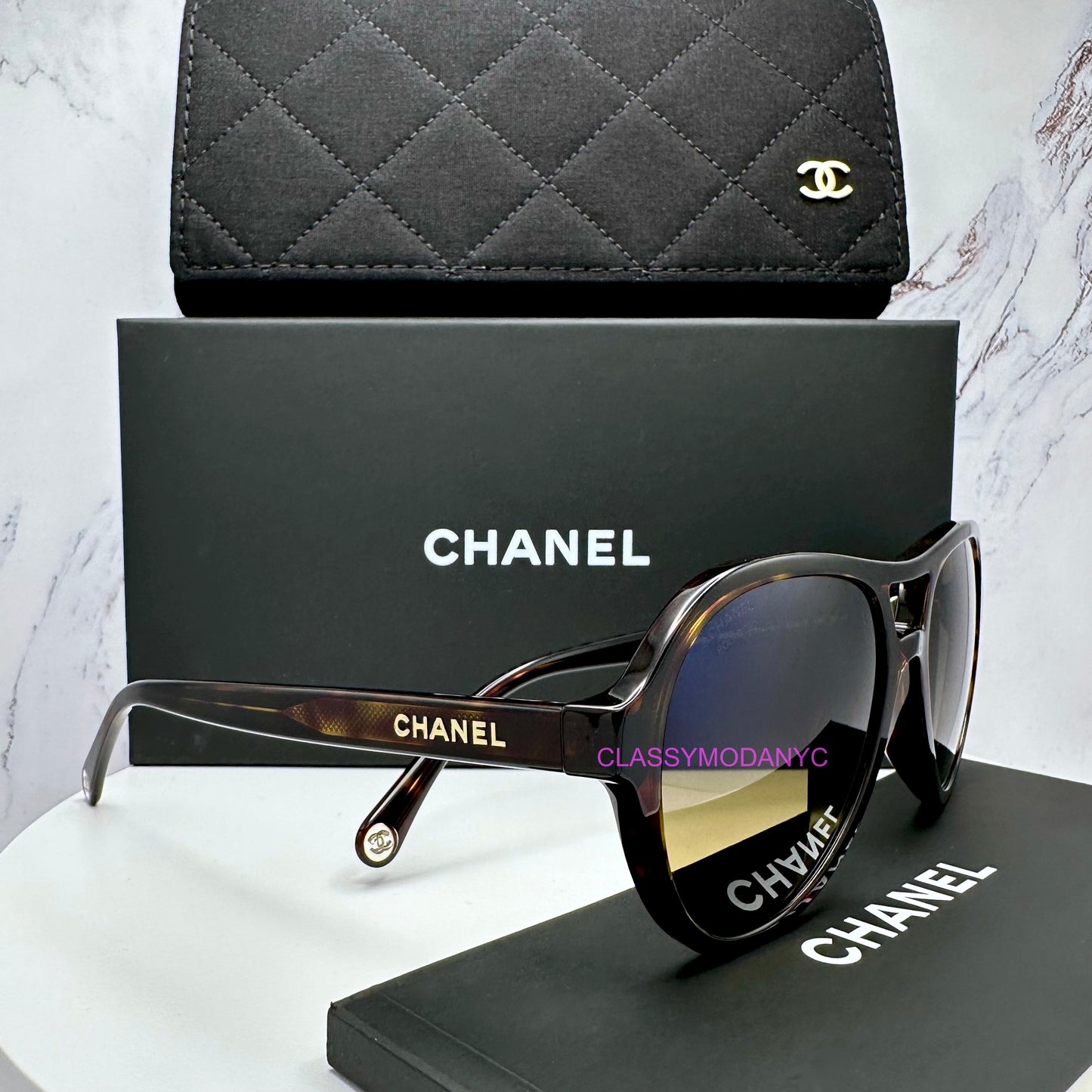 Chanel sunglasses with a black quilted case and Chanel box on a light gray background