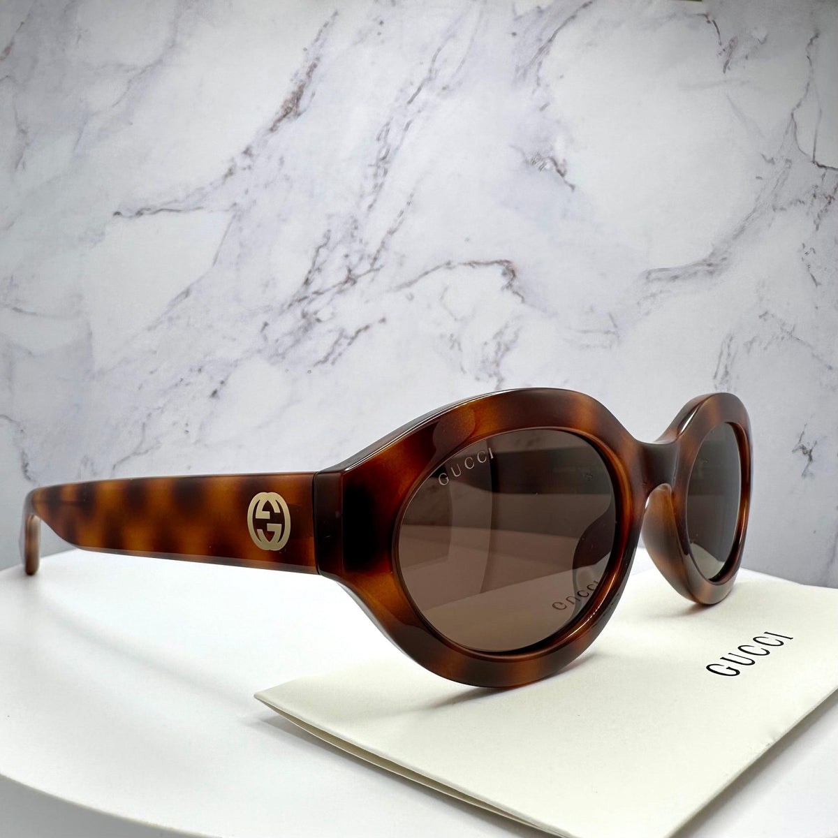 Gucci GG1579S 002 brown tortoise shell oval side view of sunglasses with Gucci authenticity card