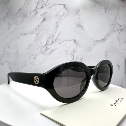 Gucci GG1579S 001 black oval side view with gold GG logo.