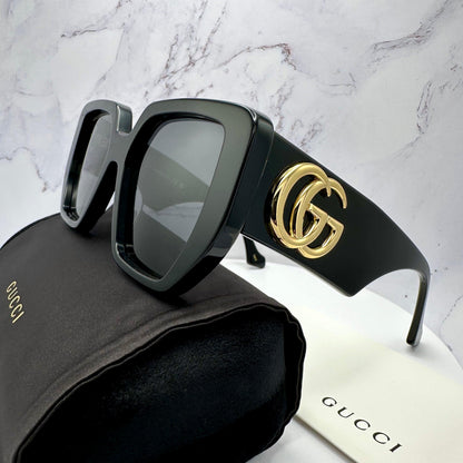 Gucci GG0956S 003 black sunglasses with gold metal logo side view on case