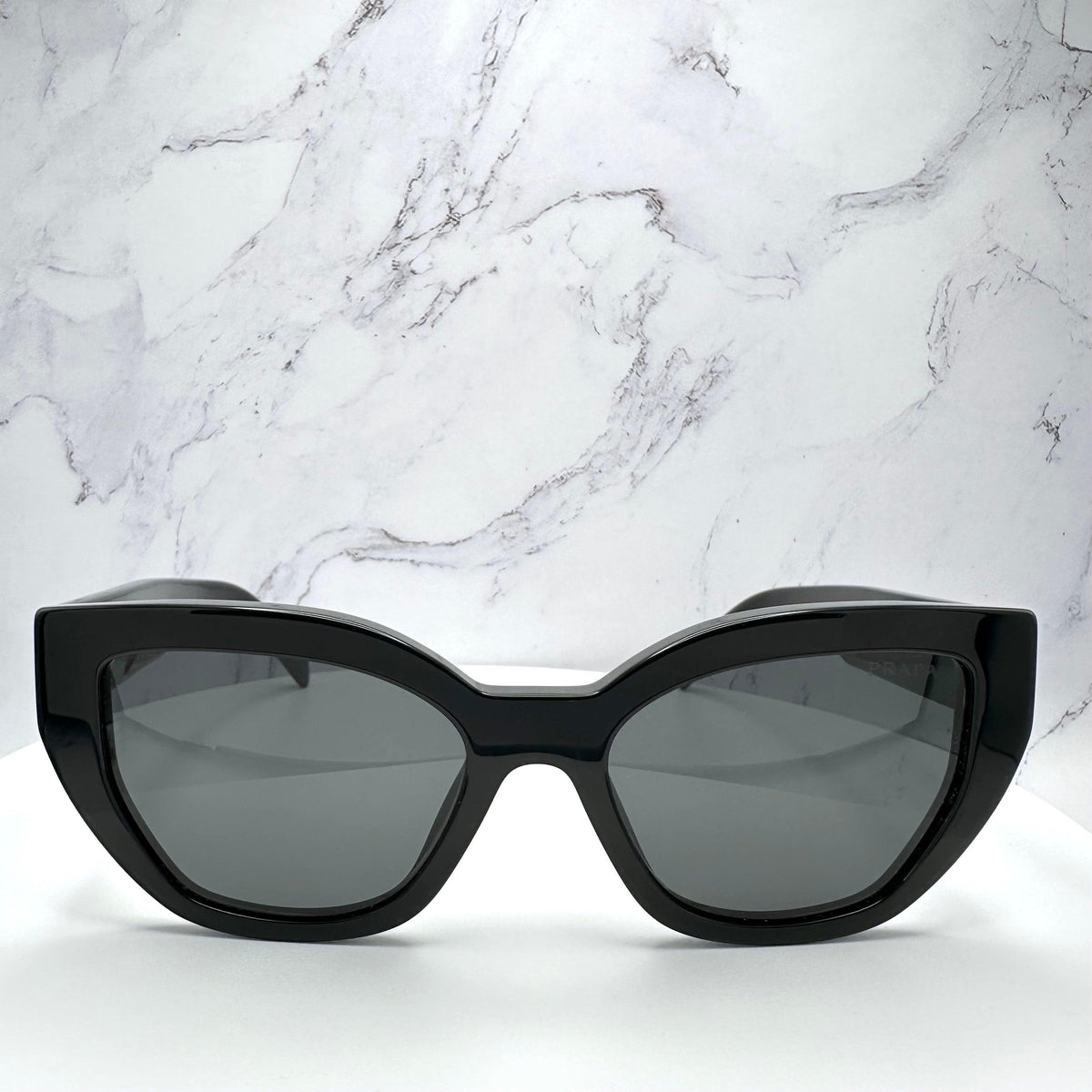 PRADA PRA09S 1AB5S0 black cat eye butterfly women’s sunglasses with gray solid lenses, silver Prada lettering and acetate frame.