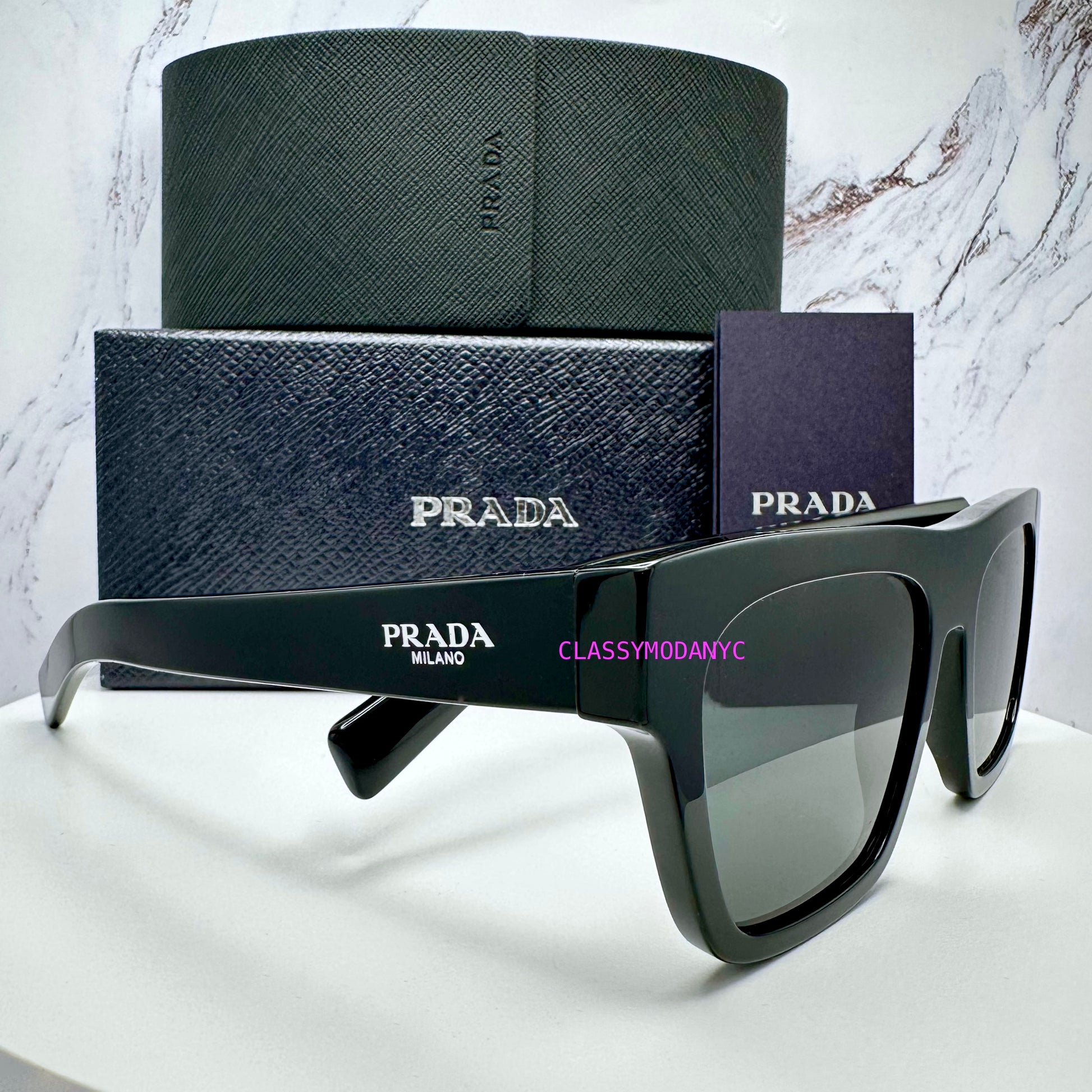 Black Prada PRC03S 16K08Z sunglasses on a white surface with a marble background with box and case 