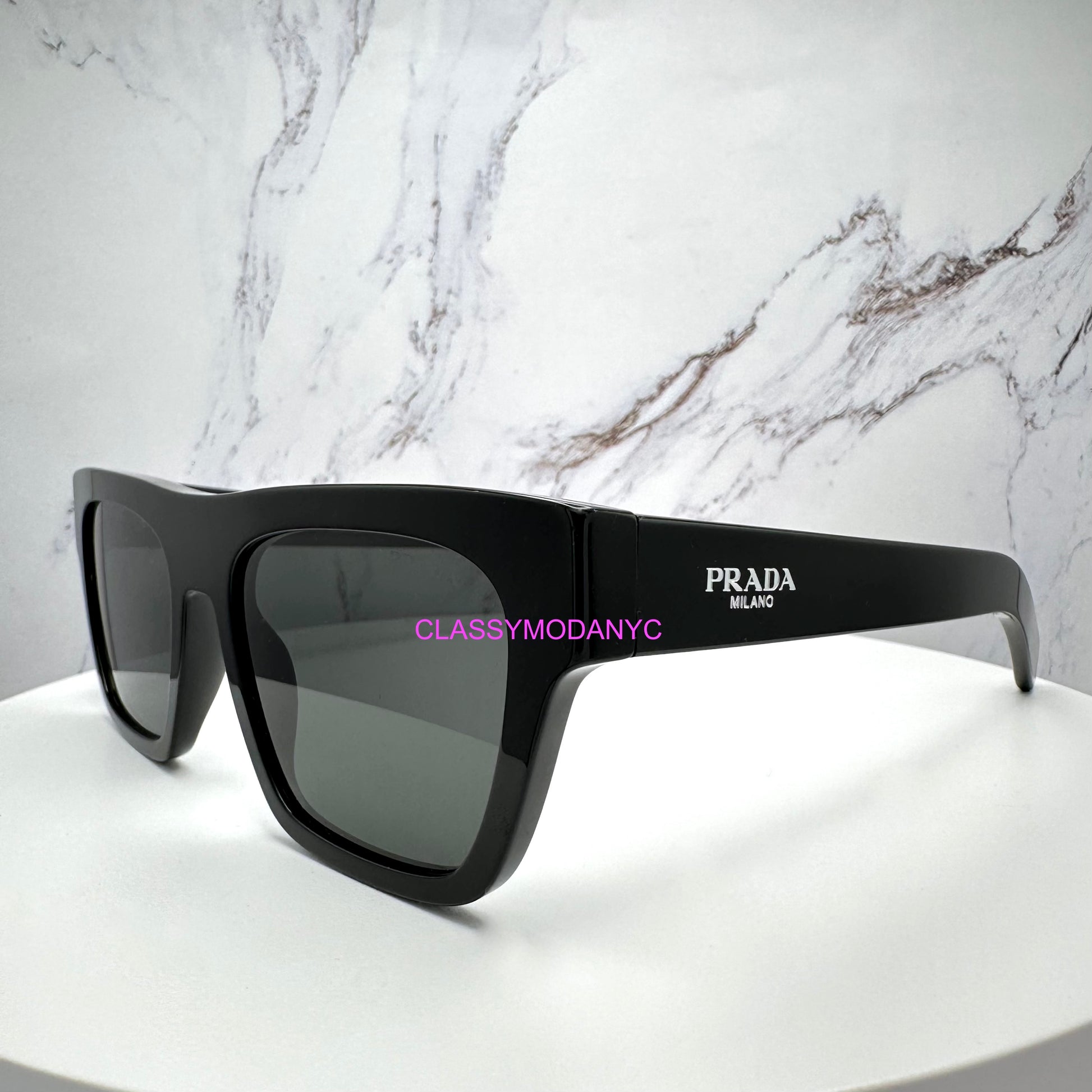 Black Prada PRC03S 16K08Z sunglasses on a white surface with a marble background 