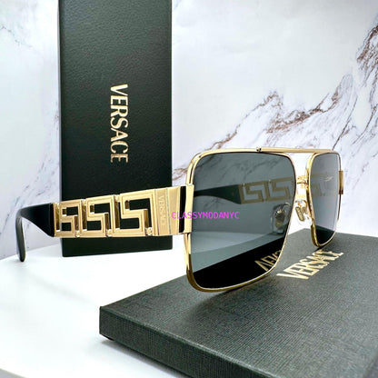 Versace sunglasses with gold frame and grey lenses on a Versace box with marble background